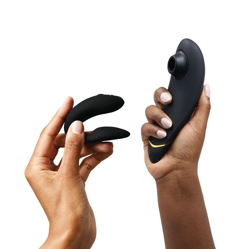 Two hands holding black massage devices against a white background